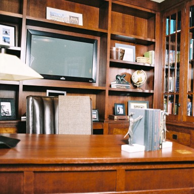 This bespoke office cabinetry with open shelving and lower file system was built in cherry wood with tiger maple inlay detail. The leather office chair swivels for access to the computer station. The pulls are Rocky Mountain Hardware. Accessories are purchased.